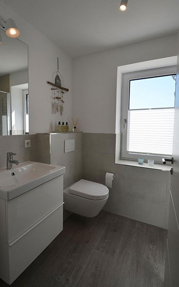 Helles Badezimmer mit Dusche, Handtuchheizkörper, Fön und Spiegel